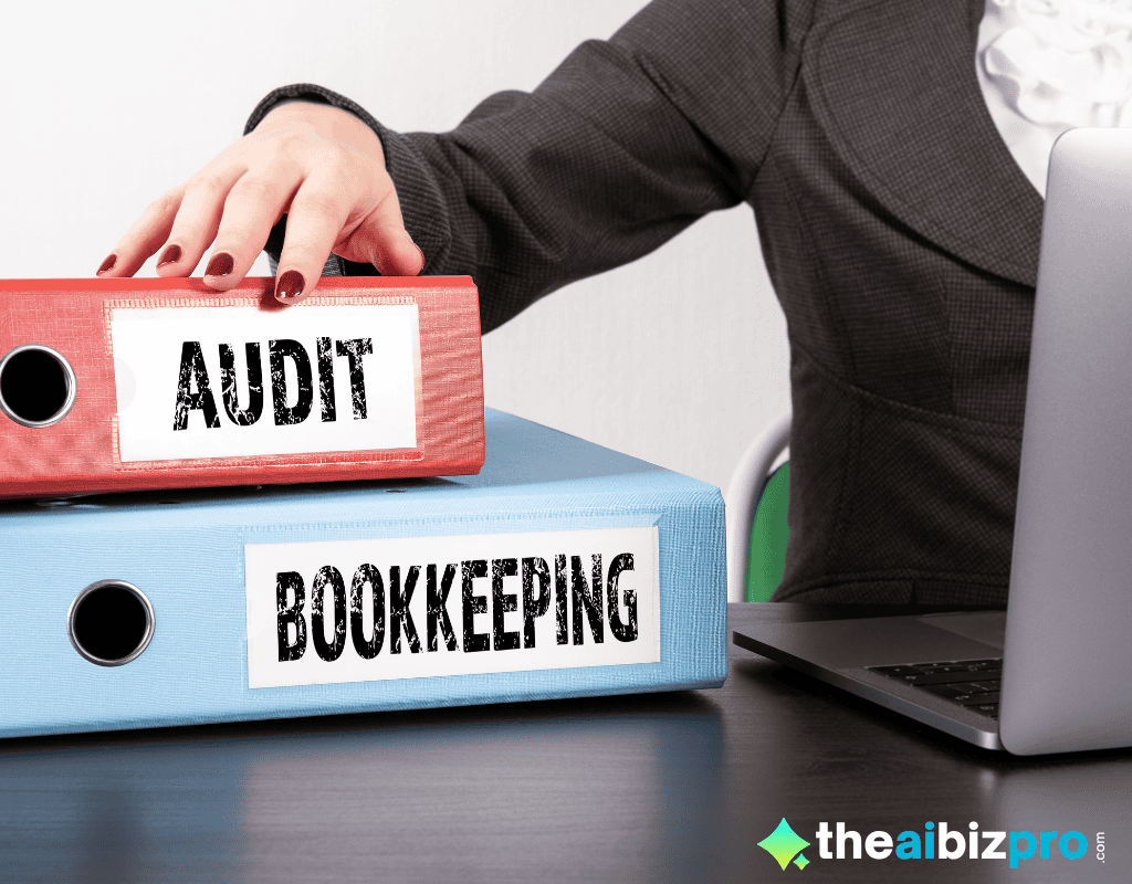 A person's hand reaching for a red binder labeled "AUDIT," with a blue binder labeled "BOOKKEEPING" underneath it, next to a laptop, symbolizing the organization of financial records enhanced by AI automated bookkeeping for small online shops.